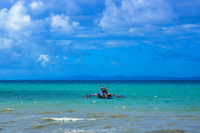 Scenic view of fishing boast in turquoise sea against sky