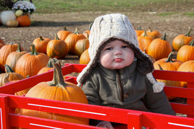 Portrait of smiling boy sitting on pumpkin during halloween