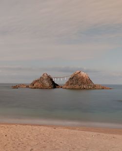 Scenic view of rocks on beach against sky