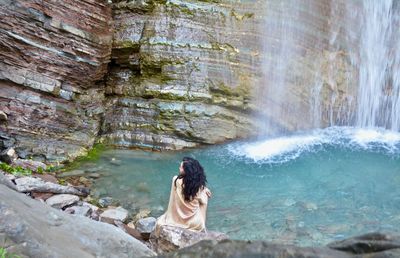 Rear view of man looking at waterfall