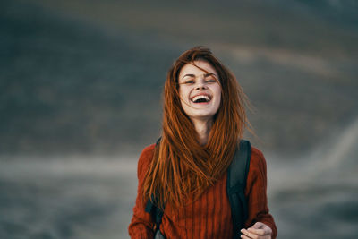 Portrait of smiling young woman standing against sea