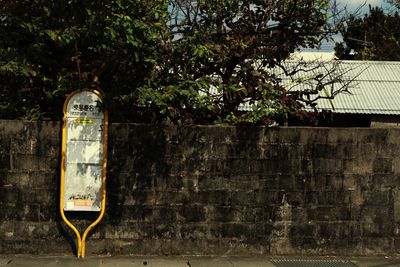 Information sign on wall by tree against building