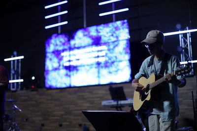 Man playing guitar on illuminated stage at night