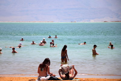 People swimming in sea against sky