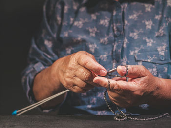 Midsection of person knitting while sitting at table