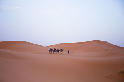 People walking in desert against sky