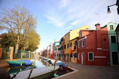 Boats on street by buildings against sky