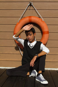 Low angle view of young man sitting on pier