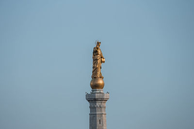 Low angle view of beautiful statue of golden madonna with blue sky in background