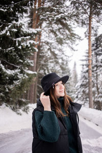 Young woman standing against trees