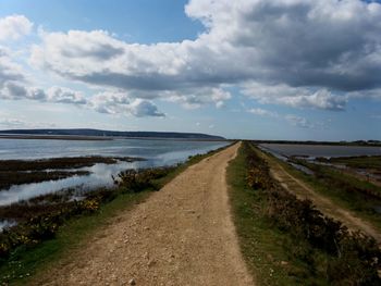 Road amidst land against sky