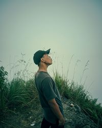 Side view of man standing on field against sky