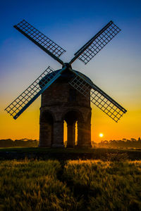 Traditional windmill on field against sky at sunset