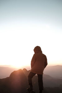 Rear view of man standing against sky during sunset