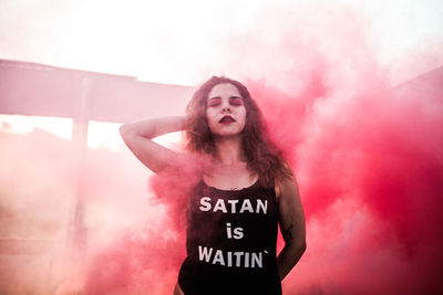 Young woman standing amidst red smoke