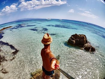 Rear view of shirtless man in sea against sky