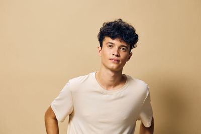 Portrait of young woman standing against yellow background
