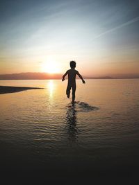 Silhouette man standing on beach against sky during sunset