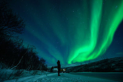 Man standing on snow covered landscape against sky at night