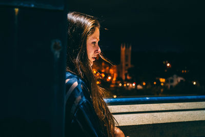 Portrait of young woman looking away at night