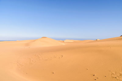 Scenic view of desert against clear blue sky