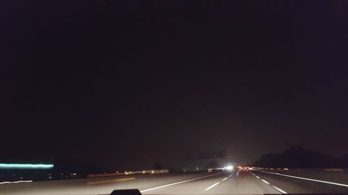 Light trails on road against sky at night