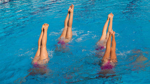 Swimmers with feet up swimming in pool