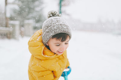 Smiling boy cleaning snow