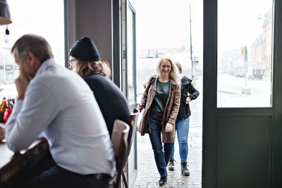 Women entering from open door while men sitting at restaurant