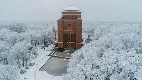 Built structure on snow covered trees against sky