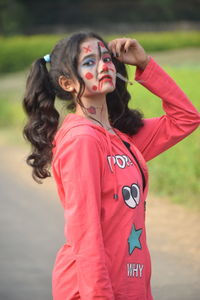 Portrait of young woman standing against blurred background