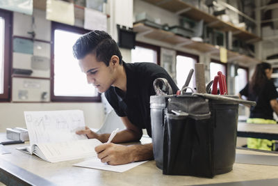 Male high school student taking notes in training class