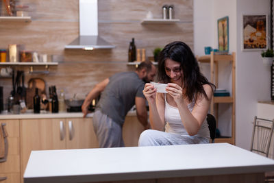 Couple arguing while standing in kitchen at home