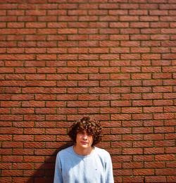 Portrait of young man against brick wall