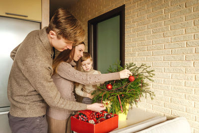 Family decorating the christmas tree against wall