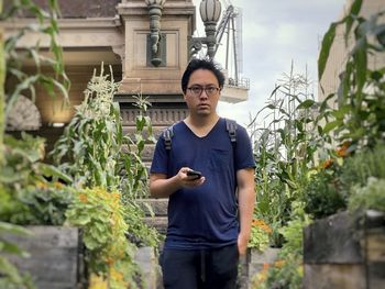 Portrait of young man standing against plants