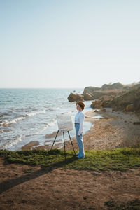 Full length of man standing on beach against clear sky