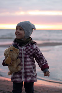 Rear view of woman standing against sky during sunset