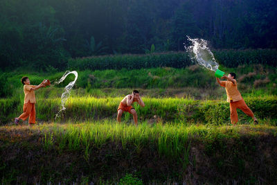 Boys throwing water on friend over grassy field