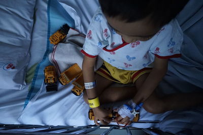 High angle view of child playing on bed in hospital