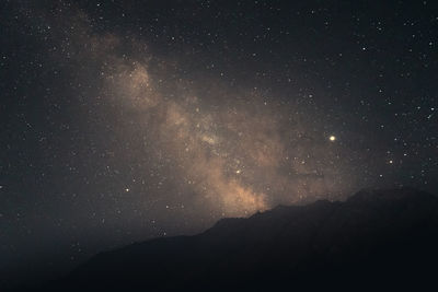 Low angle view of silhouette mountain against sky at night