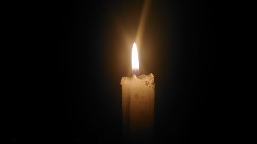 Close-up of lit candle over black background