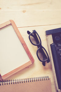 Directly above shot of typewriter with book and eyeglasses on table