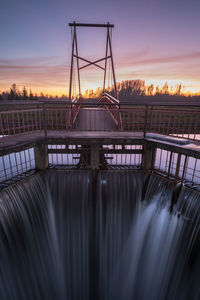 Bridge over river against sky during sunset