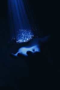 Close-up of hands in illuminated water at night
