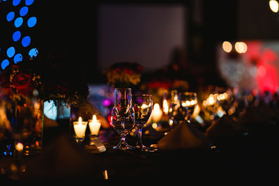 Close-up of illuminated candles and wineglasses on table
