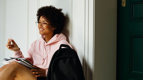 Young afro woman using digital tablet against white wall