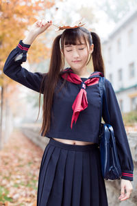 Beautiful young woman holding leaf standing outdoors