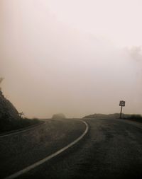 Country road against sky during foggy weather