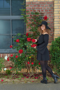 Full length portrait of woman standing by flowering plants